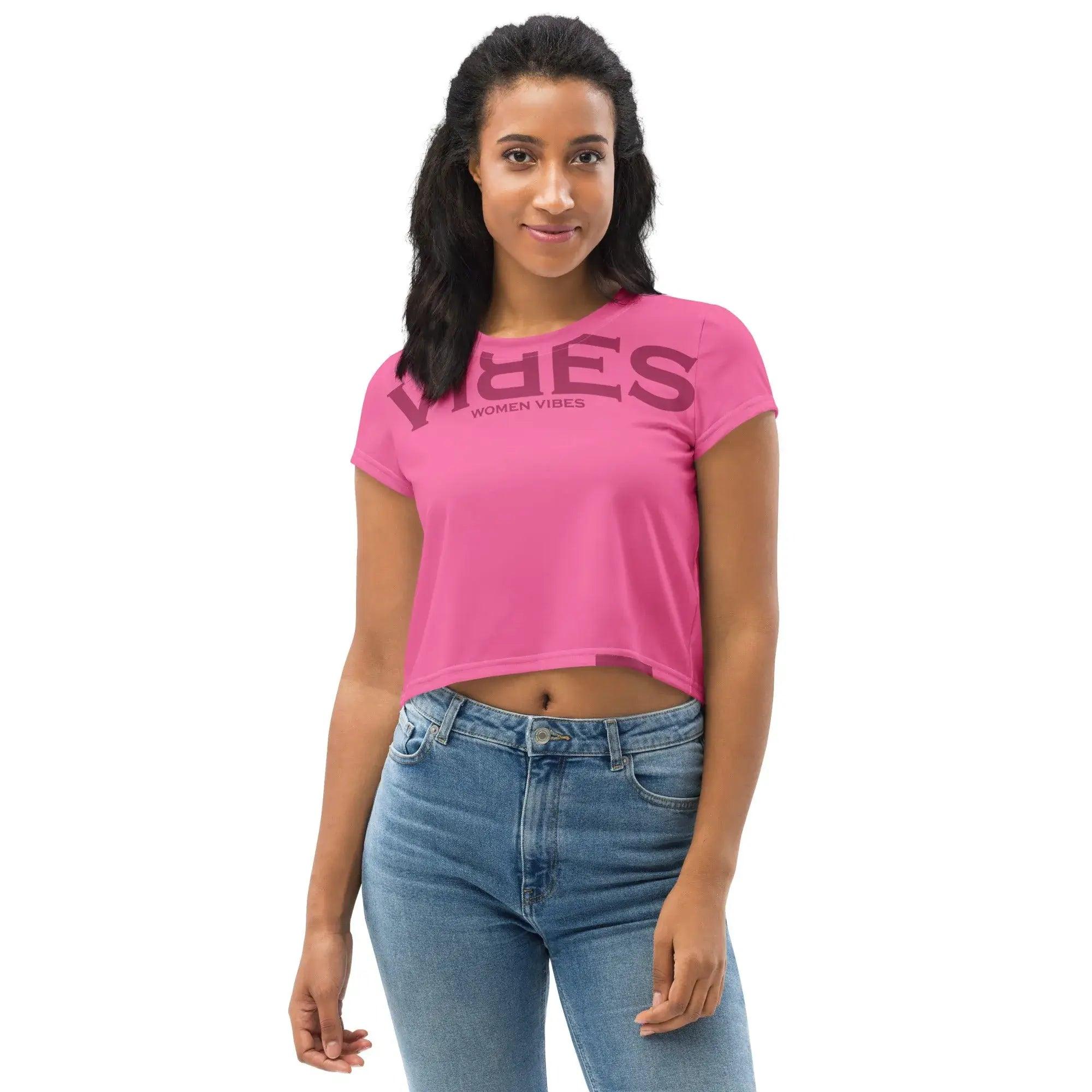 Frau trägt pinkes Crop Top mit Aufschrift VIBES WOMEN VIBES und blaue Jeans vor weißem Hintergrund.