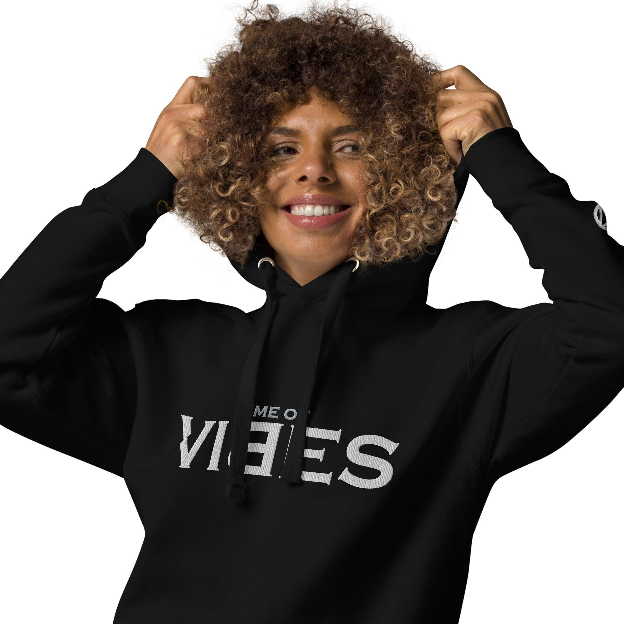 Lächelnde Frau mit schwarzem VIBES Hoodie, weißem Druck, Kapuze und lockigen Haaren