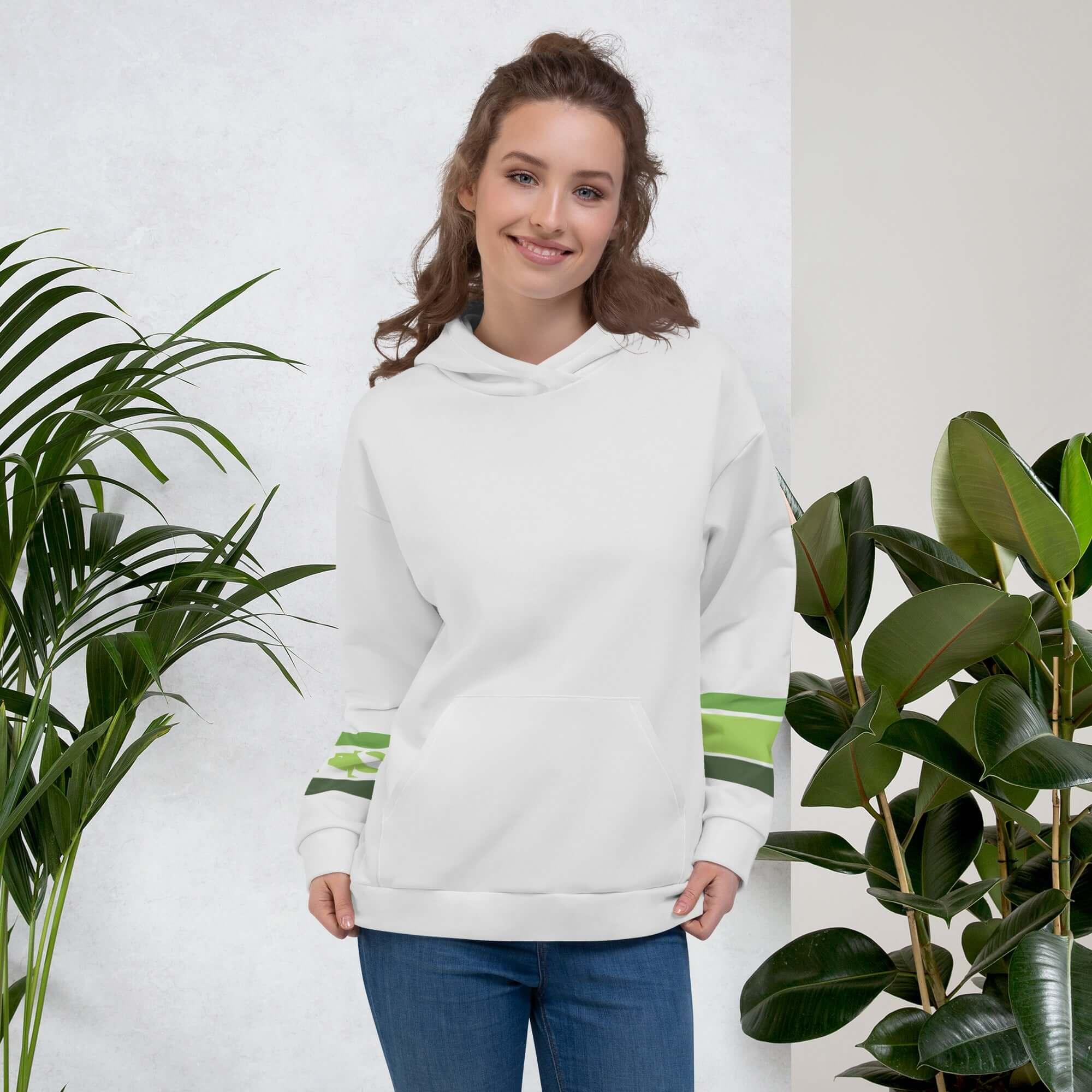 Frau trägt hellgrauen VIBES Hoodie mit grünen Streifen, vor weißen Wänden und Zimmerpflanzen