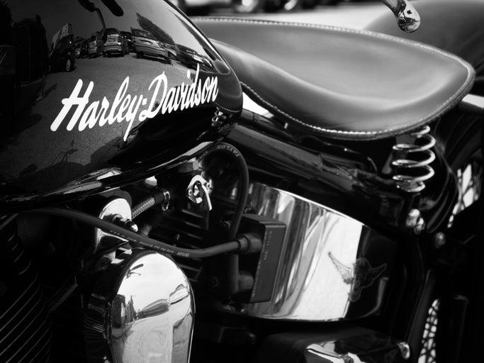 Schwarz-weiß Foto eines Harley-Davidson Motorrads mit sichtbarem Logo und Ledersattel