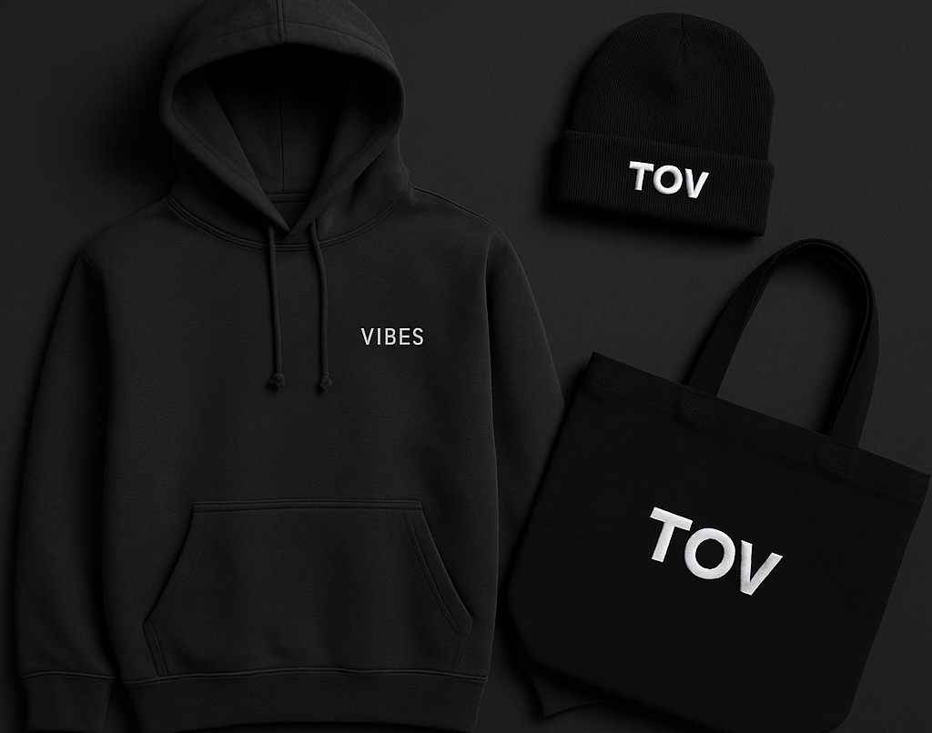 Schwarzer Hoodie mit 'VIBES', schwarze Mütze und Tasche mit 'TOV' Schrift auf schwarzem Hintergrund.