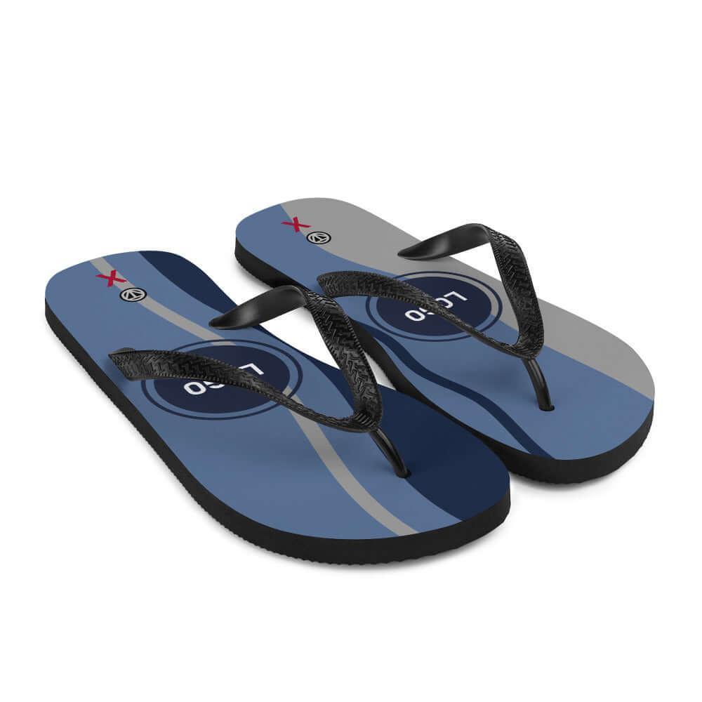 Blaue Flip Flops mit modernen Streifen und schwarzem Riemen auf weißem Hintergrund