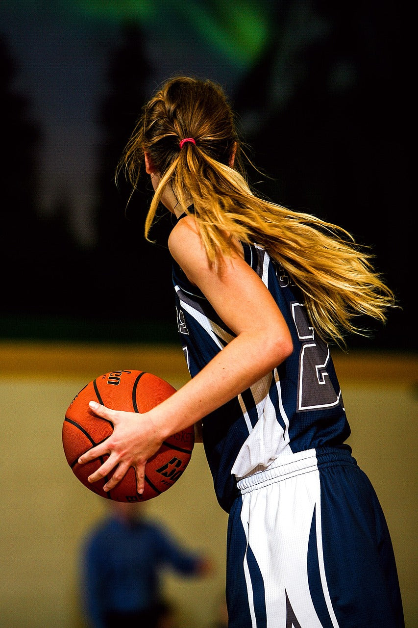 Basketballspielerin mit Ball, dunkelblaues Trikot, personalisierbare Sportbekleidung