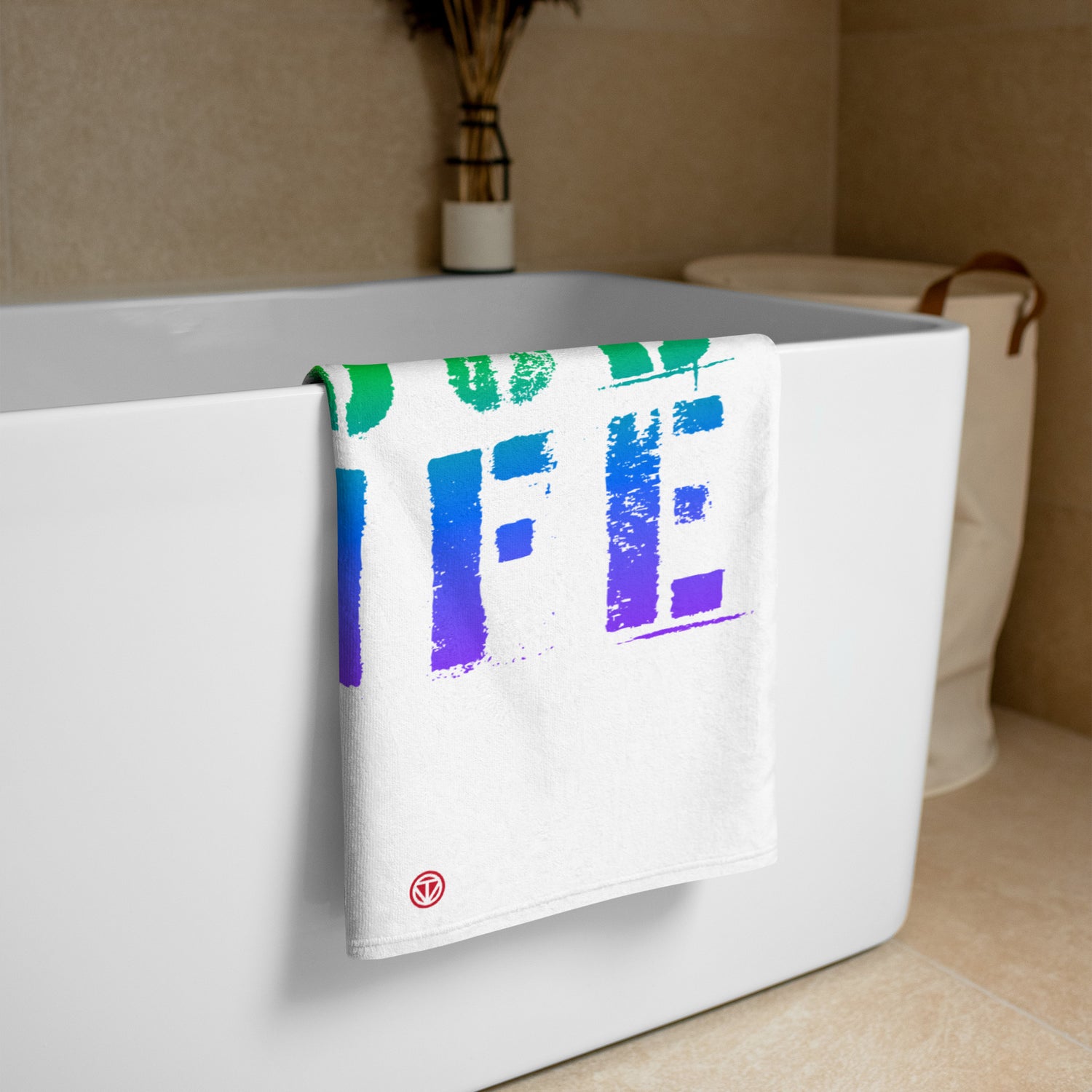 Weißes Badetuch mit buntem Farbverlauf-Design hängt an moderner weißer Badewanne in hellem Badezimmer