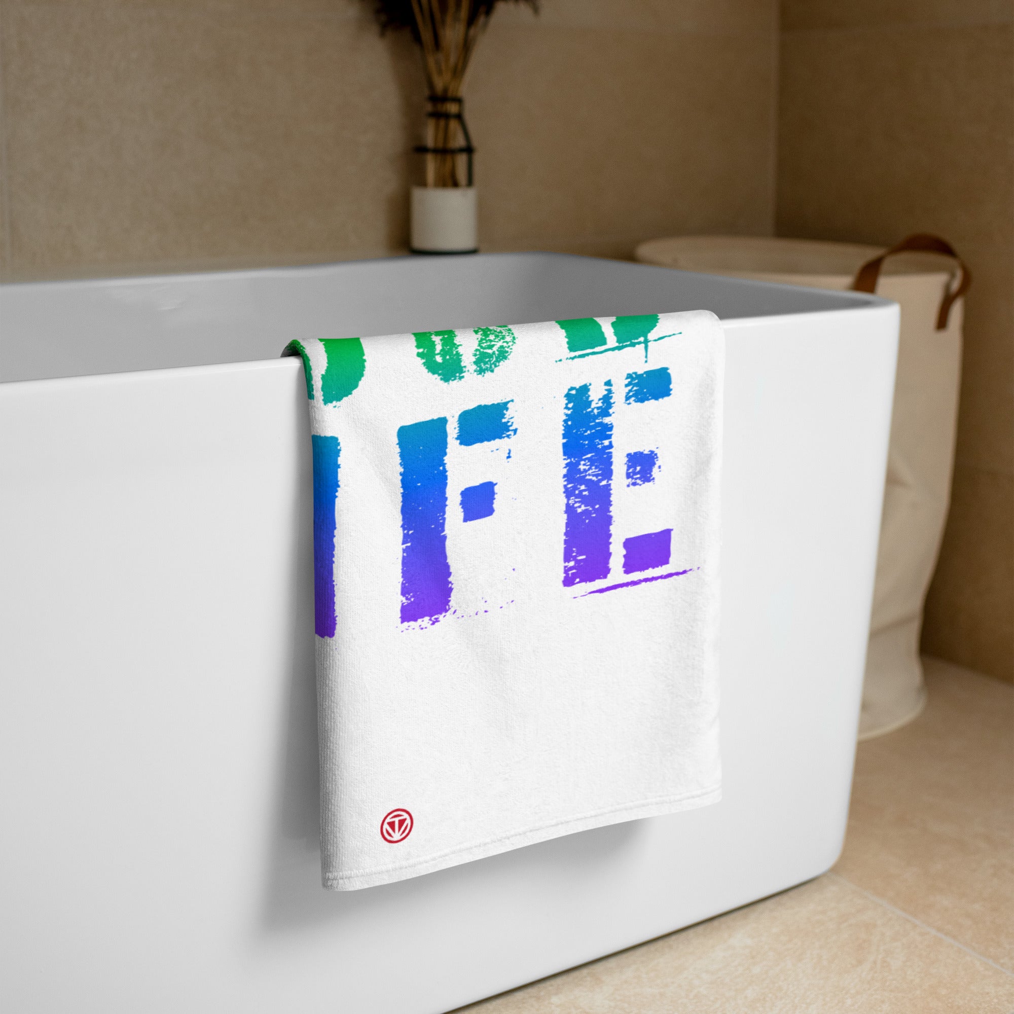 Weißes Badetuch mit buntem Farbverlauf-Design hängt an moderner weißer Badewanne in hellem Badezimmer