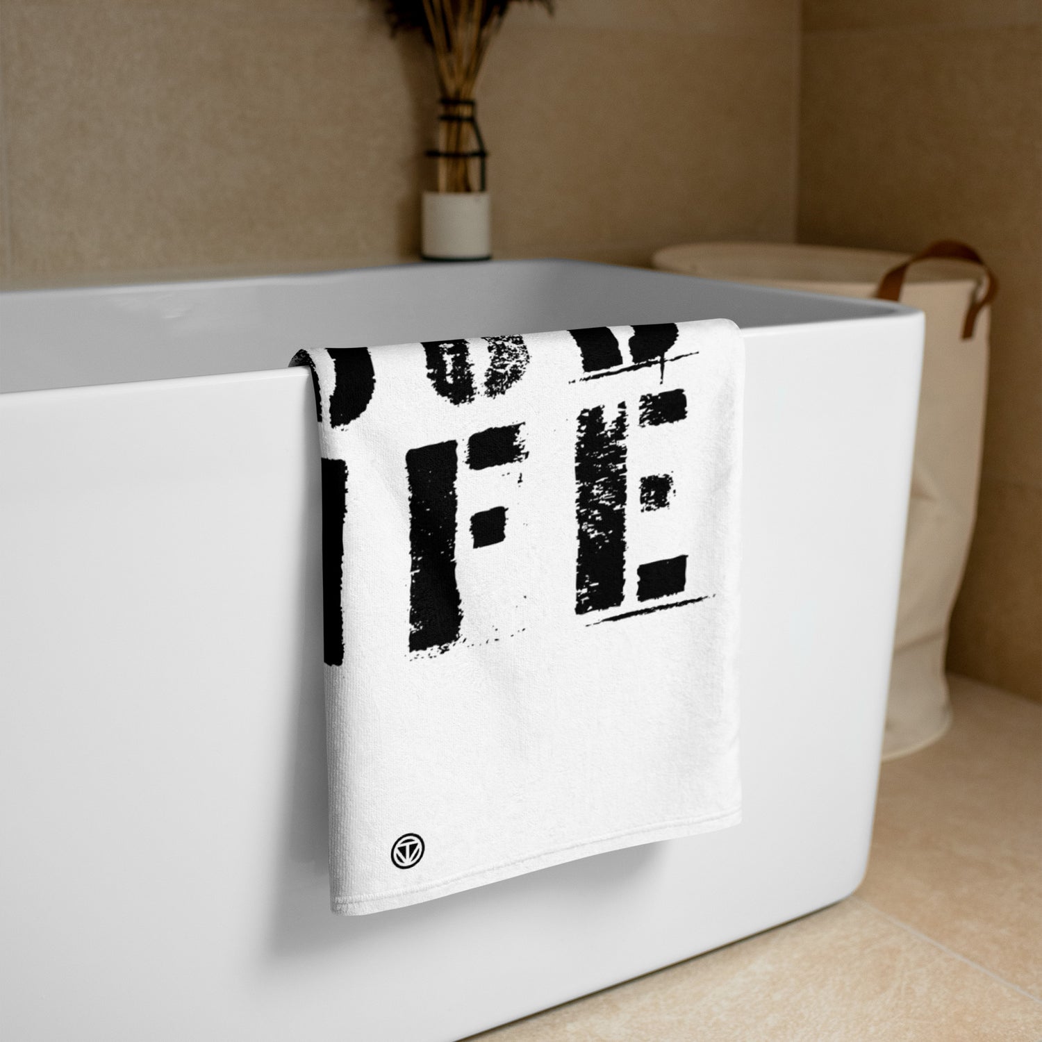 Weißes Frottee-Badetuch mit schwarzem Schrift-Print hängt an moderner Badewanne in hellem Badezimmer