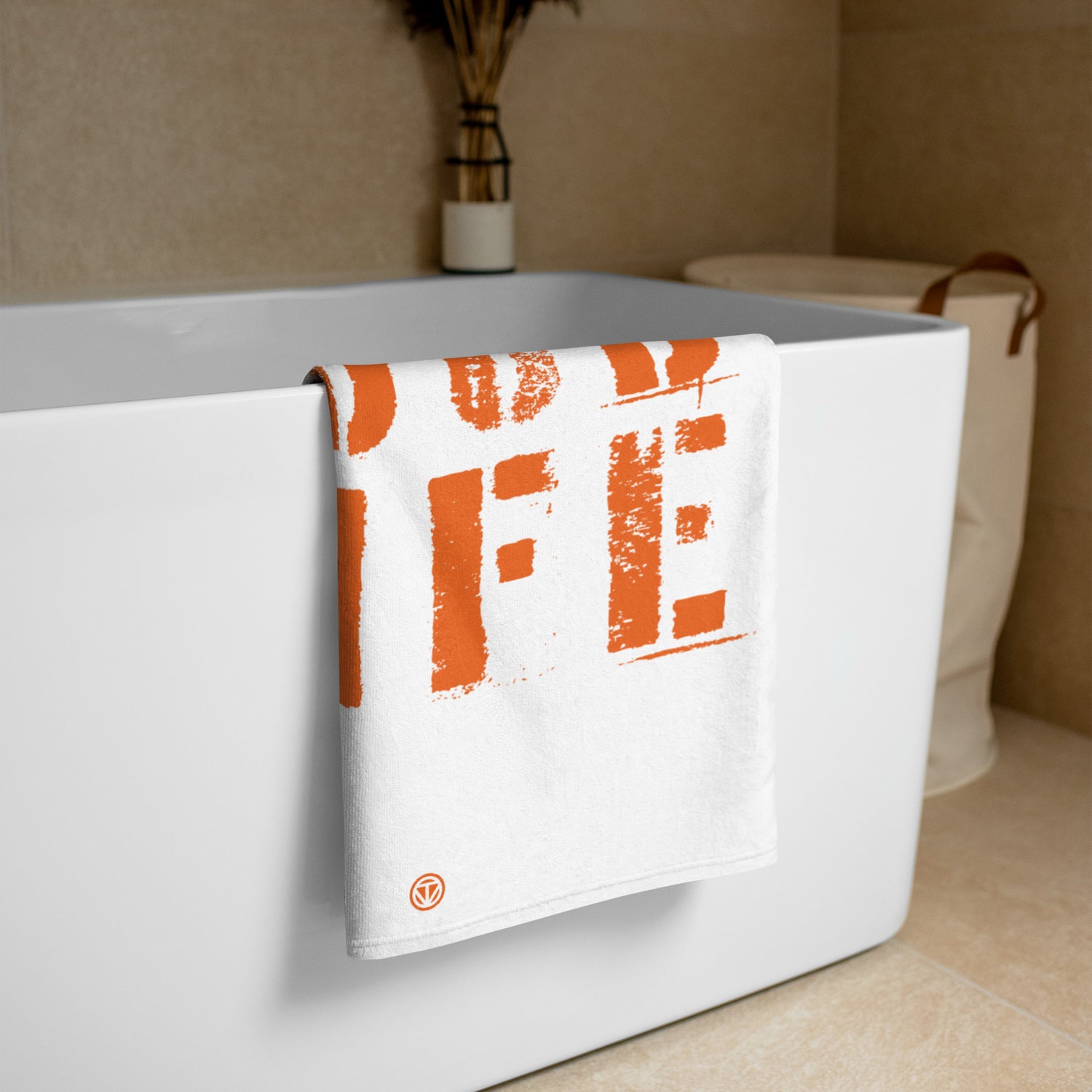 Weißes Strandtuch mit orangen Blockbuchstaben über Badewannenrand in modernem Badezimmer