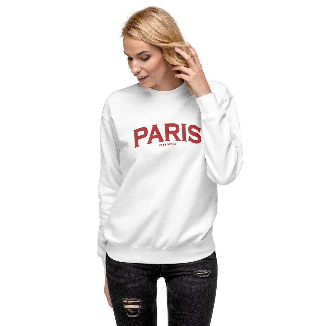 Frau trägt weißen Unisex-Sweatshirt mit rotem Paris-Schriftzug, schwarze Jeans