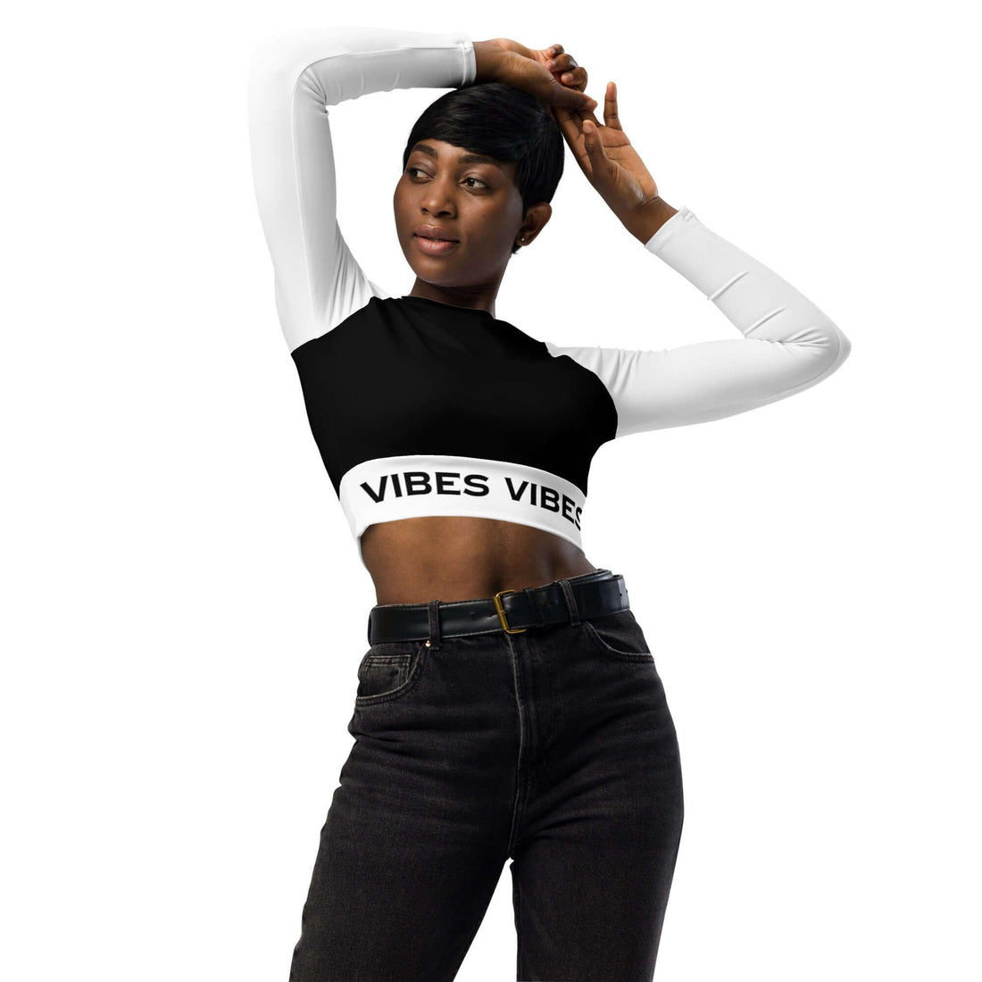 Frau trägt langärmliges Crop-Top mit Vibes-Aufdruck, High-Waist-Jeans, weißer Hintergrund